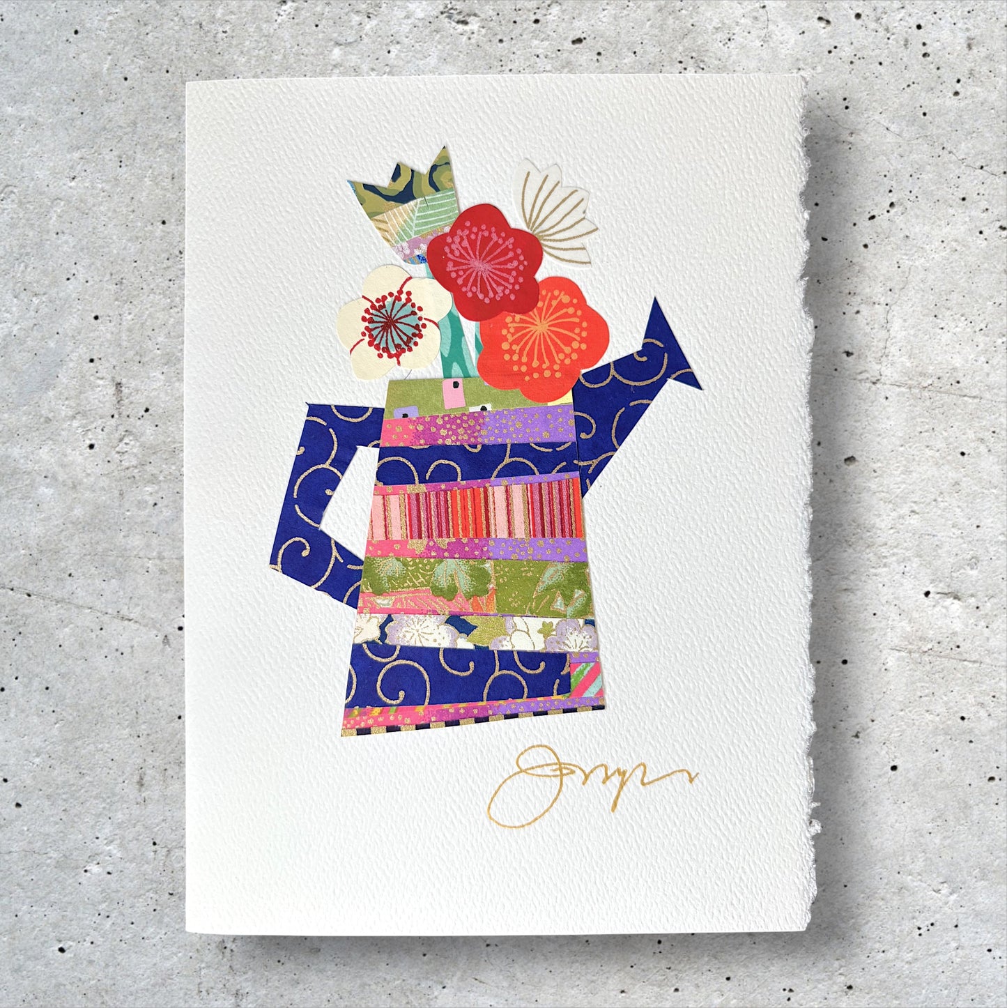 Close-up of handmade collage greeting card with floral and watering can design