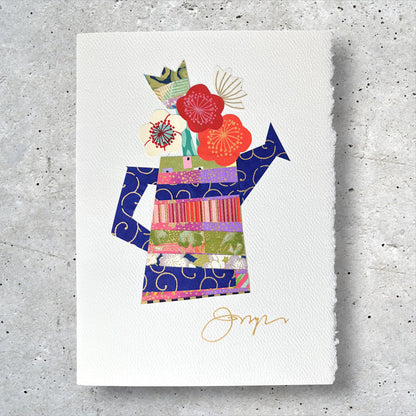Close-up of handmade collage greeting card with floral and watering can design