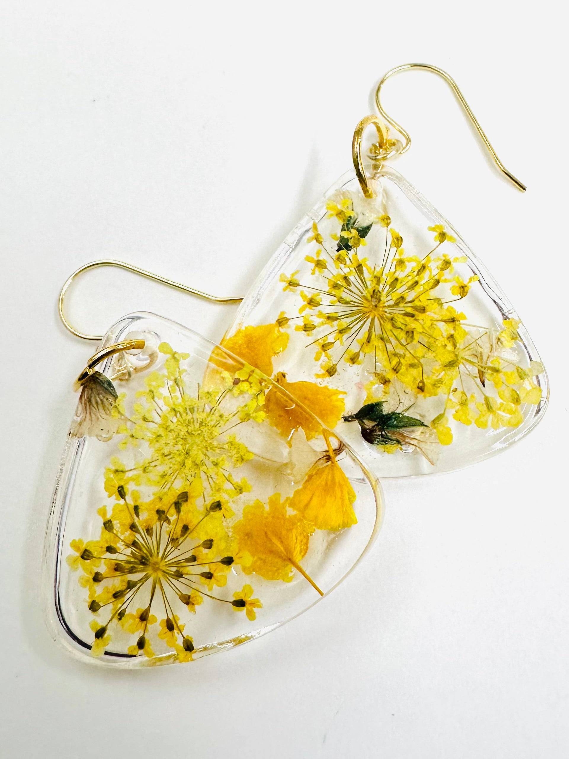 Triangle resin earrings with yellow flowers and gold hooks. Bright and cheerful real flower earrings with a sunny floral look.