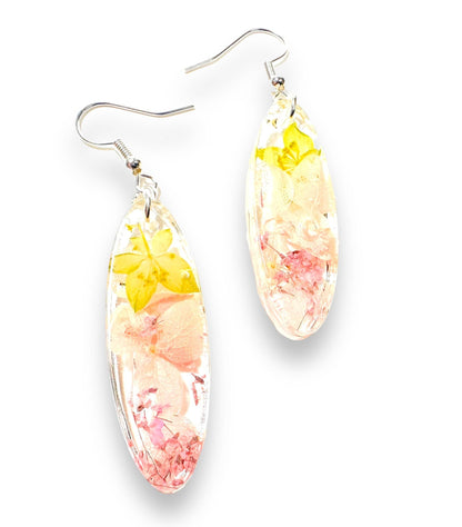 Oval resin earrings with yellow and pink real flowers and silver hooks. Delicate pressed flower earrings for a soft, floral style.