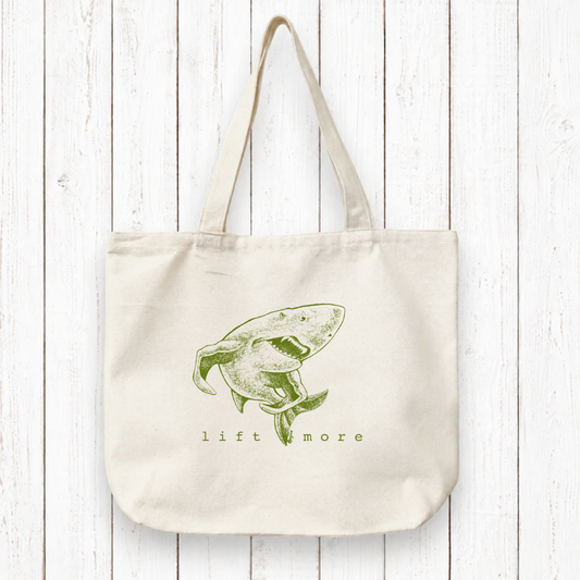Uni-T organic cotton canvas tote bag featuring a green shark illustration and the text lift more on a white background