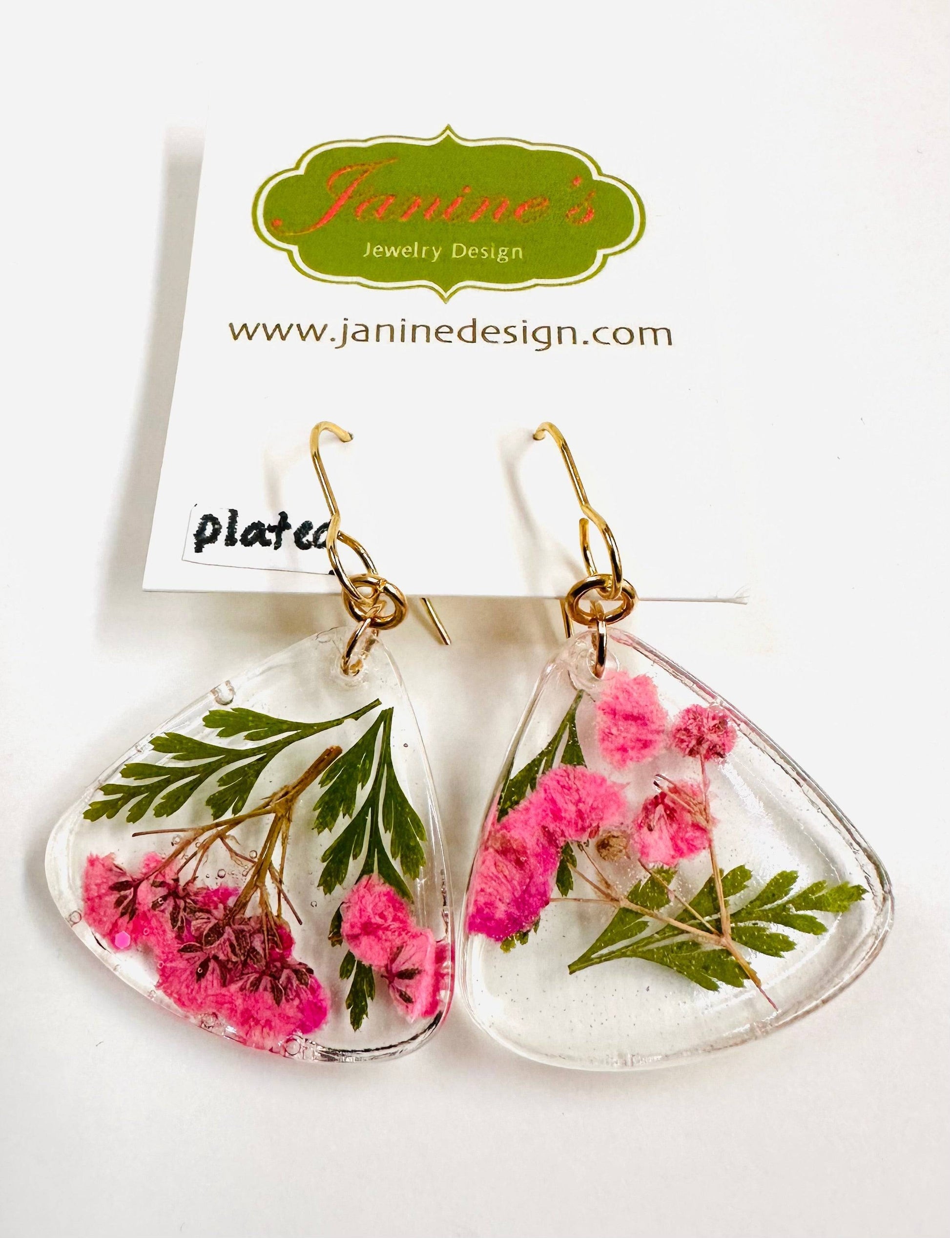Triangle resin earrings with pink flowers and green leaves and gold hooks. Delicate real flower earrings with a soft, romantic style.