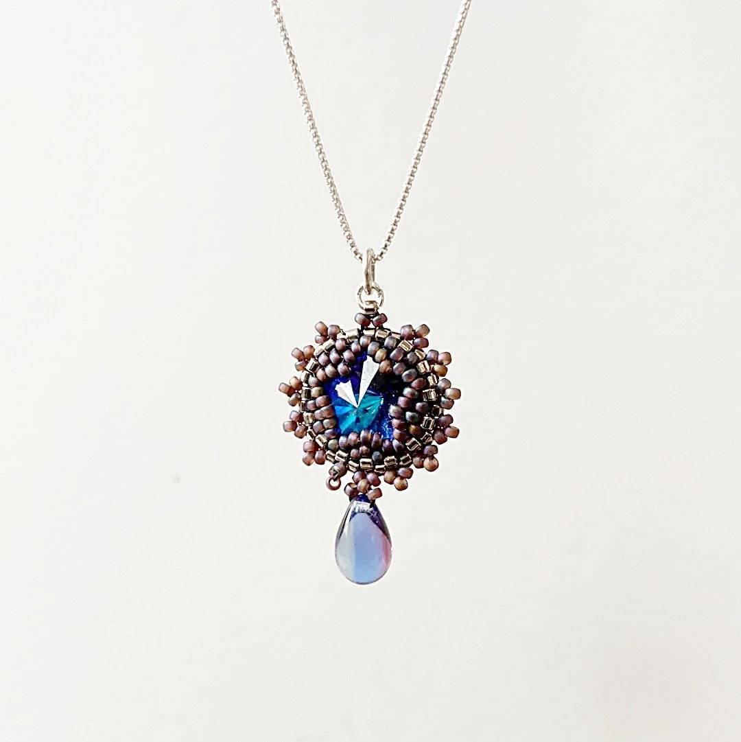 Elegant beaded crystal necklace with a round blue Austrian crystal pendant and teardrop charm, ideal for special occasions.