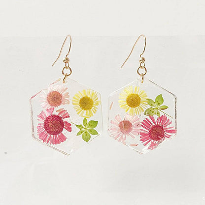 Hexagon resin earrings with multicolor real flowers and gold hooks. Floral accessory from the Real Flower Earrings collection.