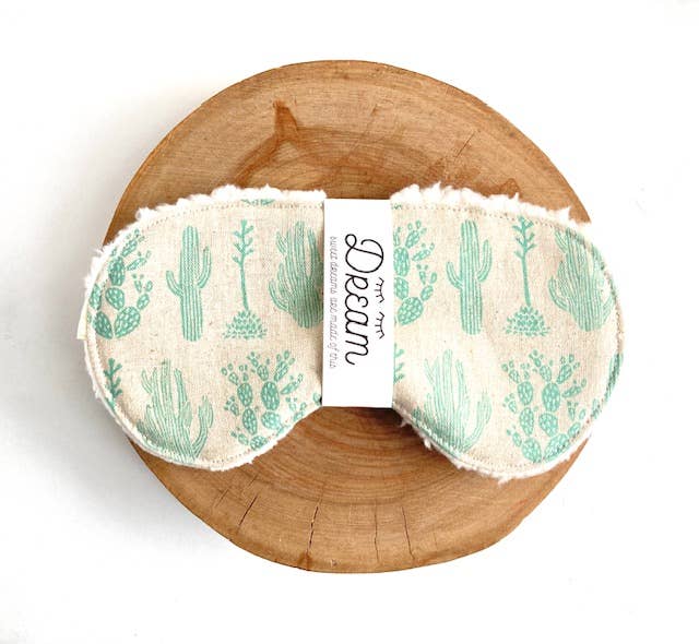 Cotton Sleep Mask Saguaro with cactus design displayed on a wooden base, offering a stylish and comfortable sleep accessory.
