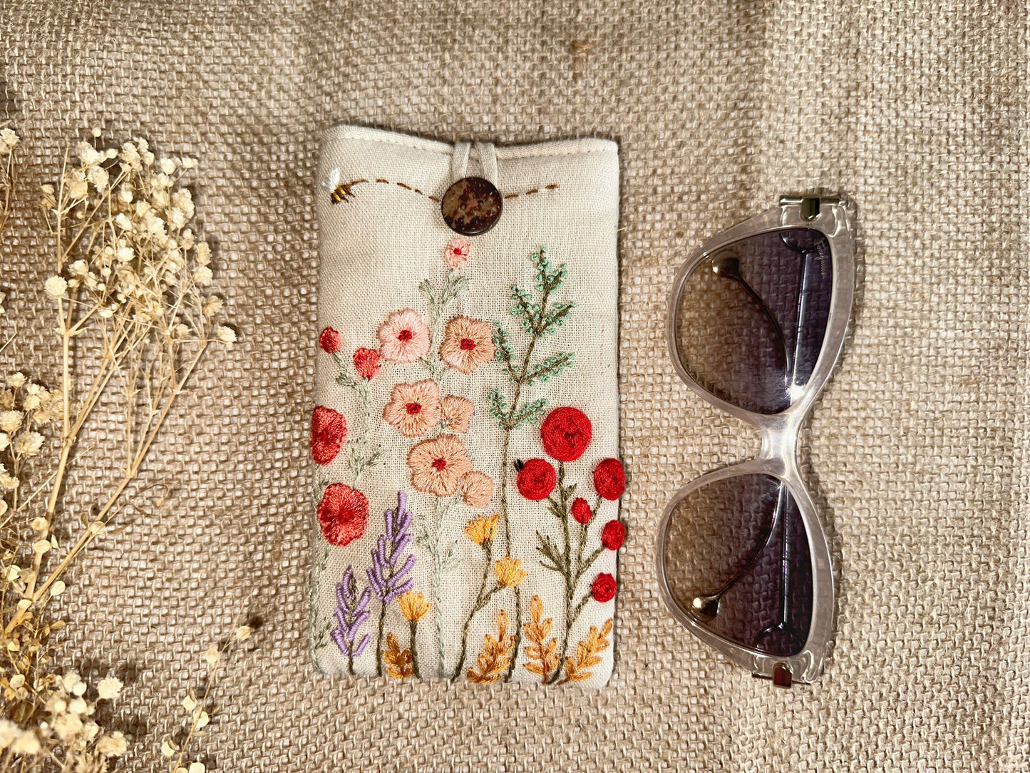 Floral embroidered linen glasses case with red and peach flowers on cream fabric, padded for stylish and safe eyewear storage.