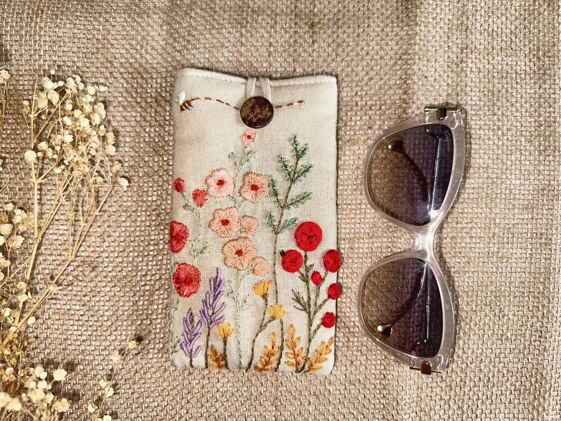 Floral embroidered linen glasses case with red and peach flowers on cream fabric, padded for stylish and safe eyewear storage.