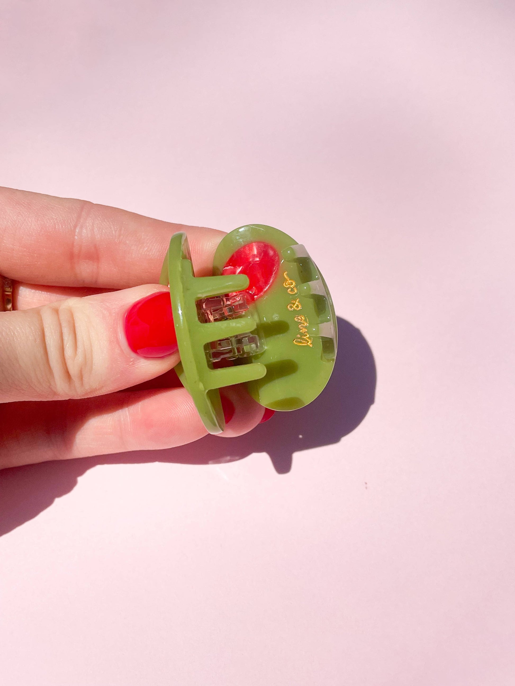 Close-up of Olive Claw Clip - Cellulose Acetate showing side view and branded engraving, emphasizing quality and compact design.