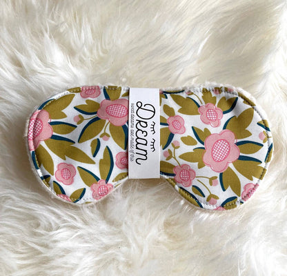Sweet Dreams Cotton Sleep Mask featuring a pink and green floral design, laid on soft white faux fur for a cozy sleep accessory.