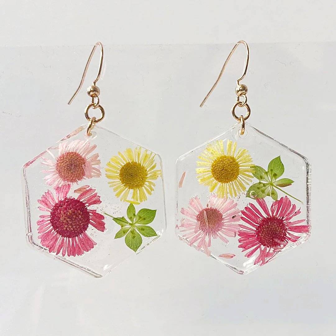 Oval resin earrings with red, pink, and yellow flowers. Gold hooks complete this delicate floral design from Pressed Flower Earrings.