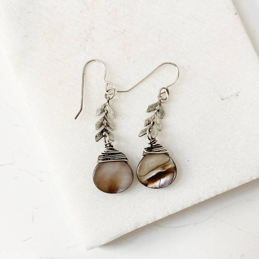 Close-up of Abalone Chevron Earrings showcasing hand-wrapped sterling silver wire and iridescent abalone drops with chevron brass accents.