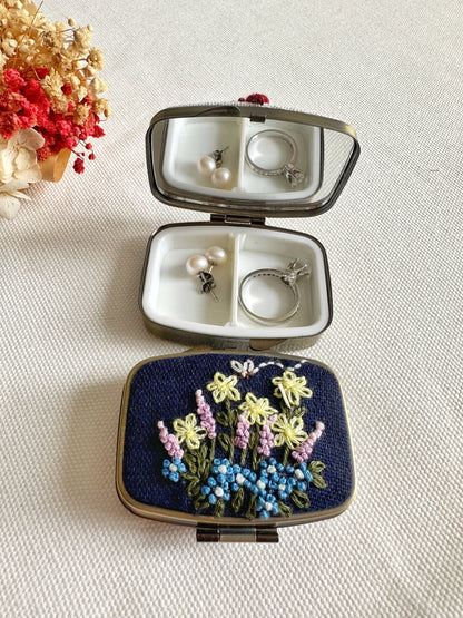 Navy Floral Embroidered Jewelry Box - Elegant Storage with yellow and blue flowers, open to reveal mirror and compartments holding earrings and a ring.