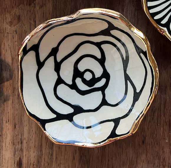Close-up of a 4" handmade ceramic dish with a rose-like black floral design and 22K gold trim, ideal for decorative or serving use.
