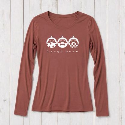 Rust-colored long sleeve T-shirt for women with white graphic design of three smiling faces with different patterns and the text 'laugh more' underneath, made from bamboo and organic cotton.