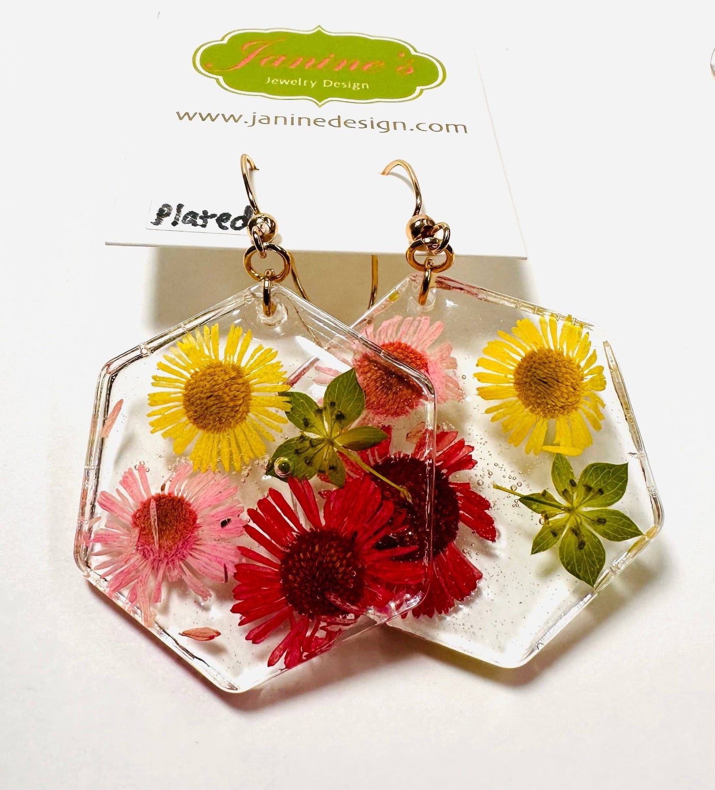 Hexagon resin earrings with red, yellow, and pink flowers and gold hooks. Bright pressed flower earrings with a cheerful look.