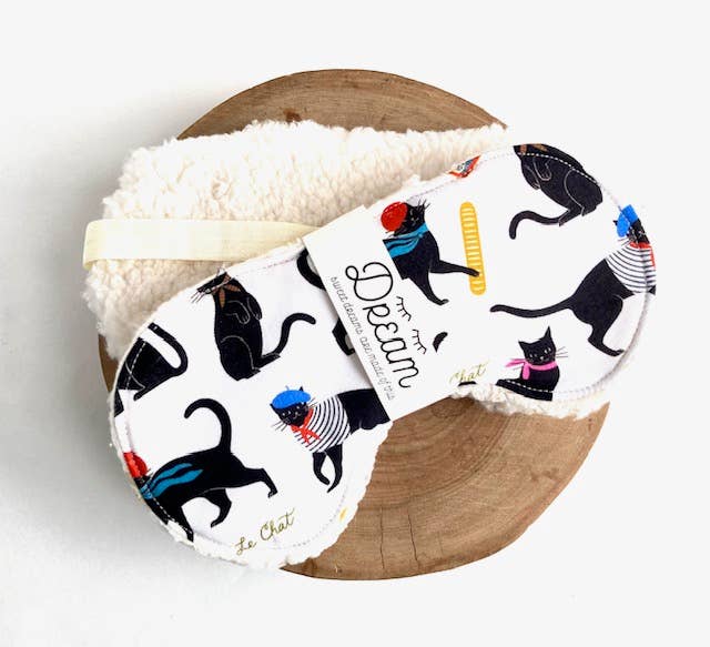 Le Chat Cotton Sleep Mask with playful black cat print on 100% cotton front and soft Sherpa back, ideal for relaxation and sleep aid.