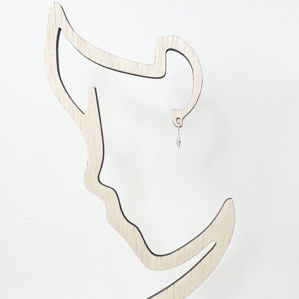 Tiny Spike Earrings-Uni-T - Sterling Silver shown on a wooden earring display shaped like a face profile, highlighting their small size.