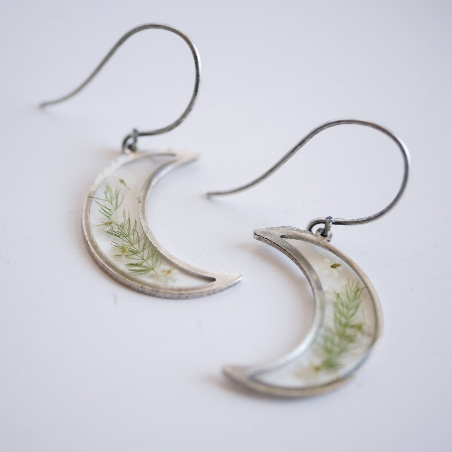 Detailed view of silver Garden Flower Earrings featuring Queen Annes Lace. Crescent moon earrings with real flowers, perfect for gifting.