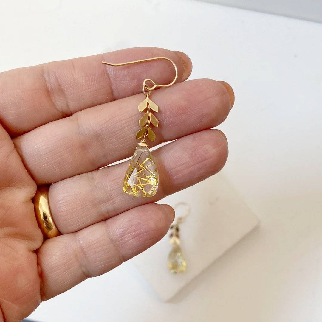 Handcrafted Rutilated Quartz Chevron Earrings shown in hand for scale, highlighting gold-filled wire and chevron brass detail in gemstone jewelry.