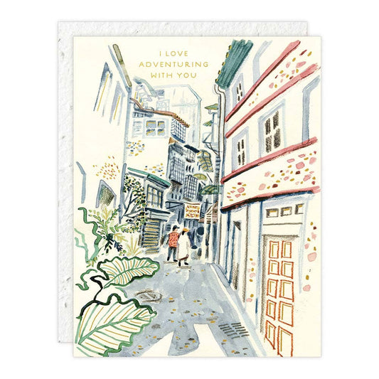 Eco-Friendly Love + Friendship Card with illustrated couple walking in a charming alley, featuring foil details and plantable seed paper envelope.