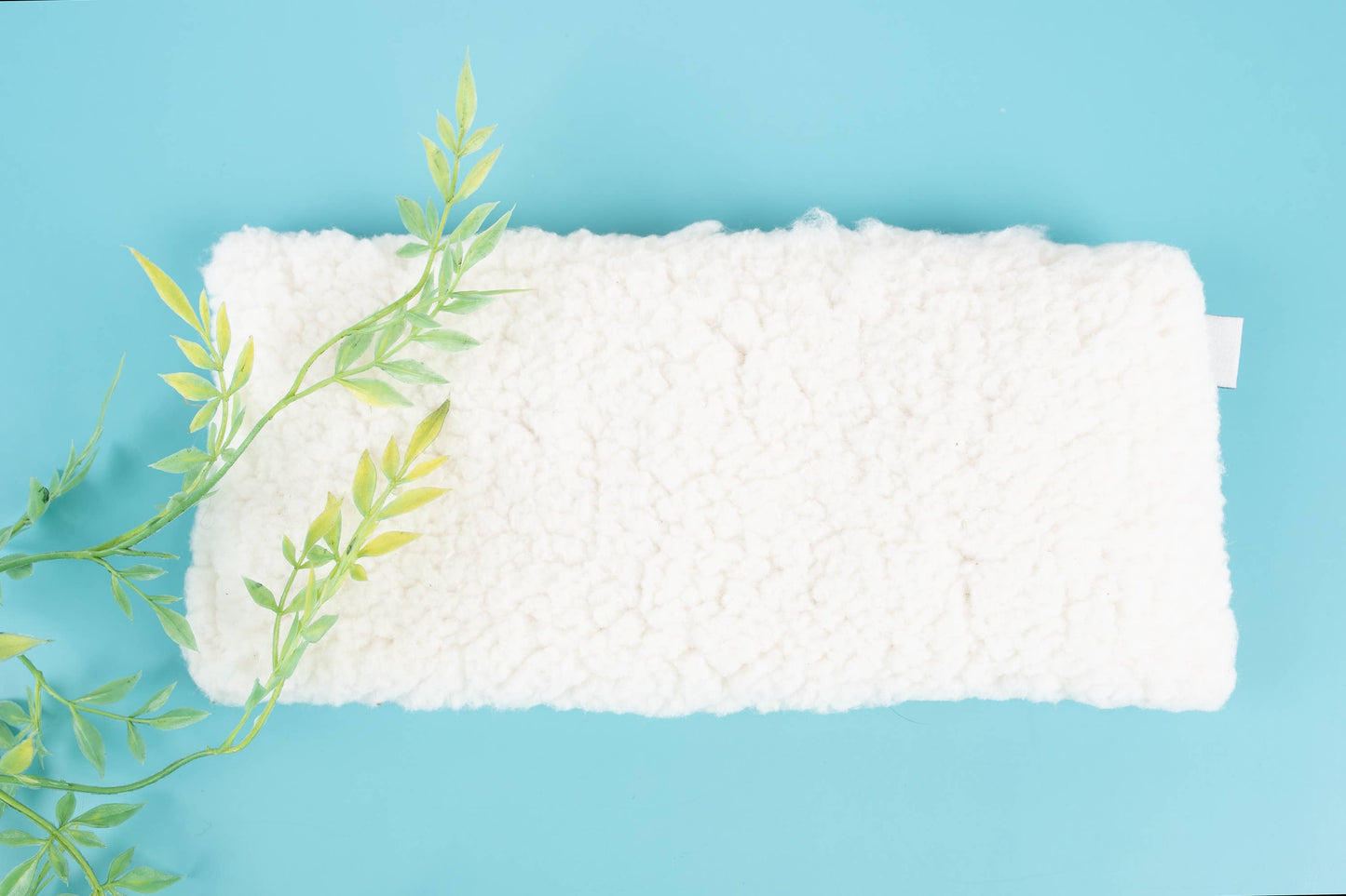 Close-up of the sherpa minky side of the Deep Rest Eye Pillow on a blue background, emphasizing its plush, soothing texture.