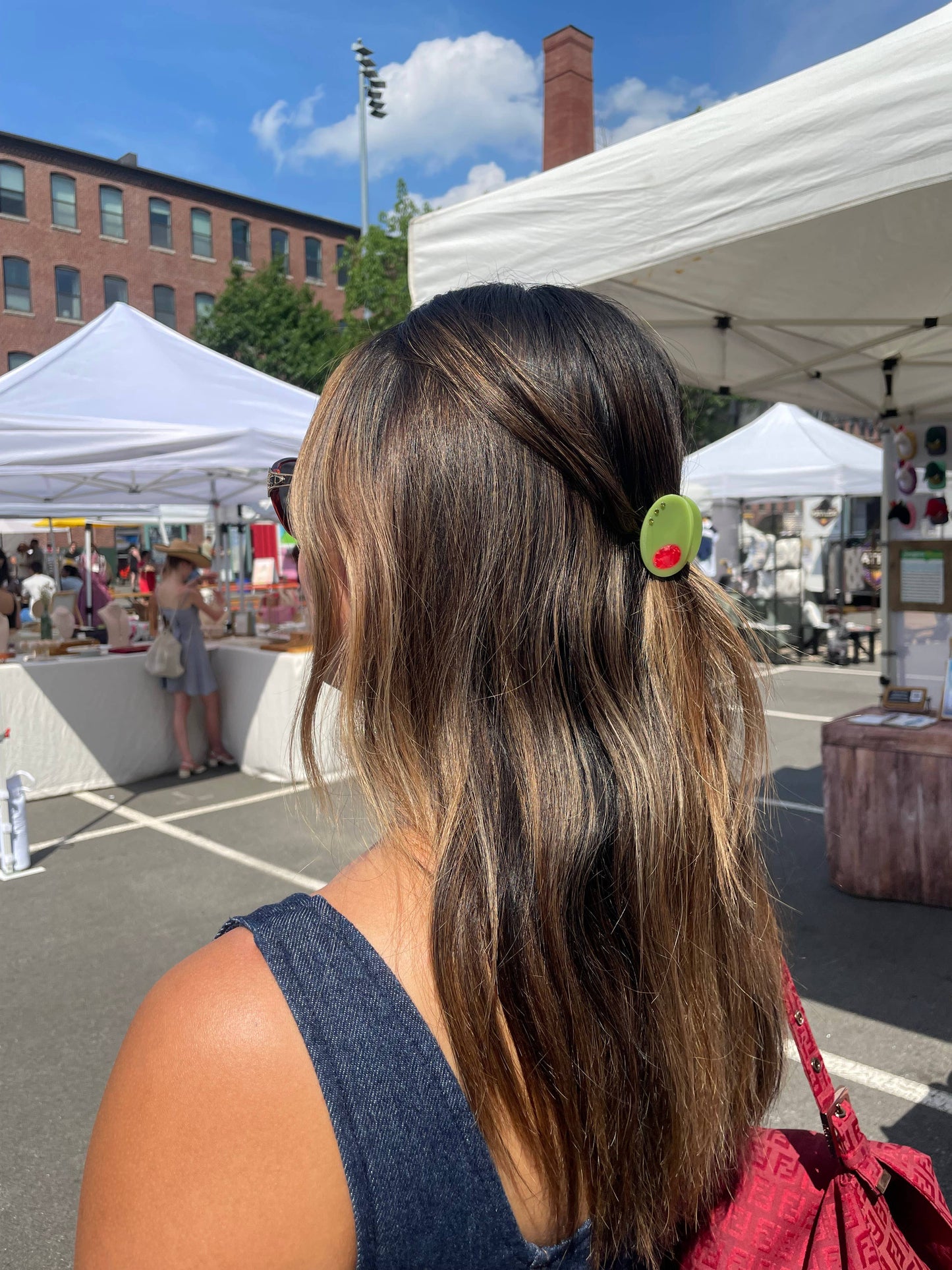 Olive Claw Clip - Cellulose Acetate worn in hair at an outdoor market, demonstrating its stylish and functional use in casual settings.