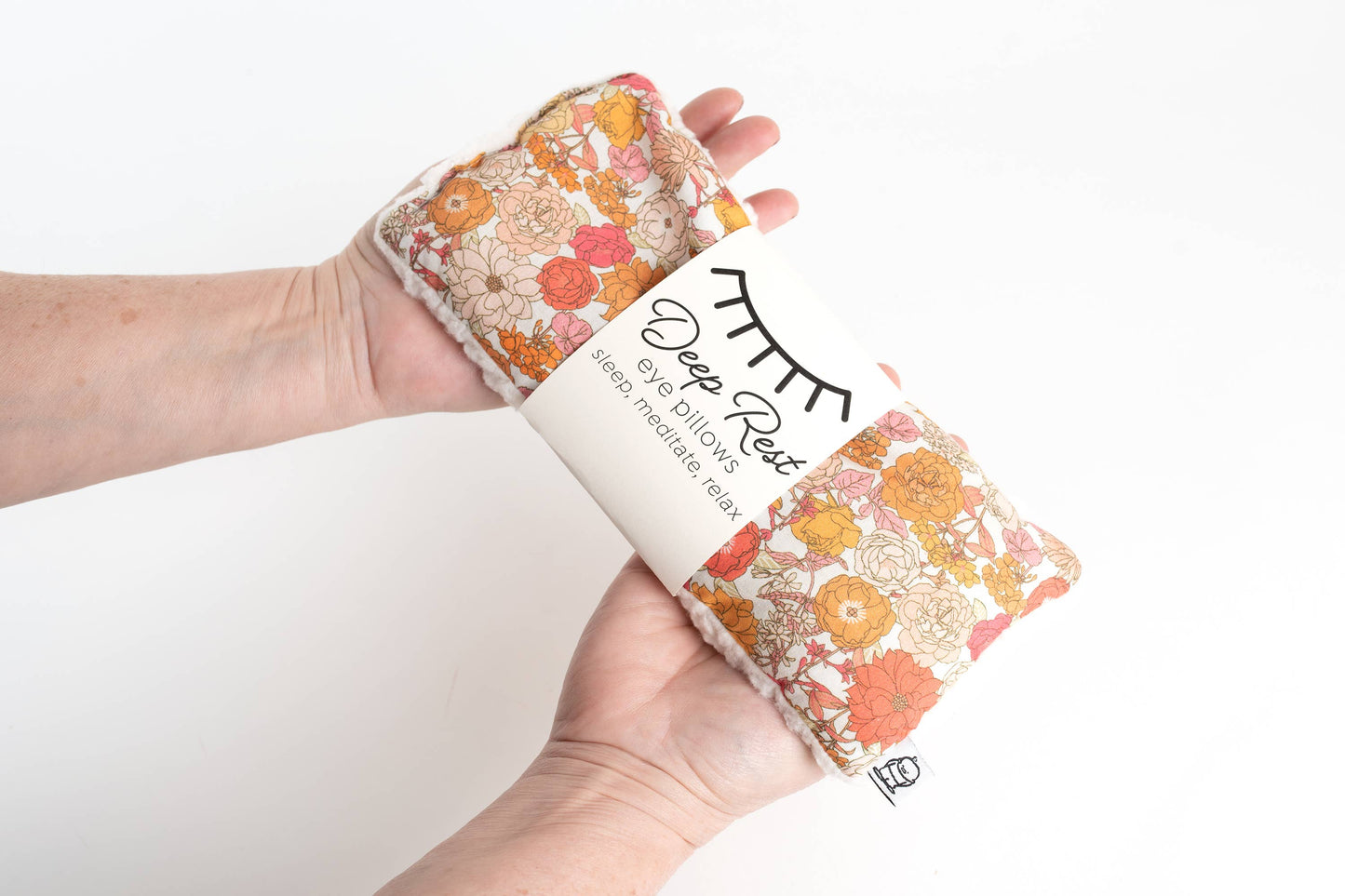 Hand holding Liberty Weighted Eye Pillow in floral design, perfect for tension relief, anxiety reduction, and restful sleep routines.