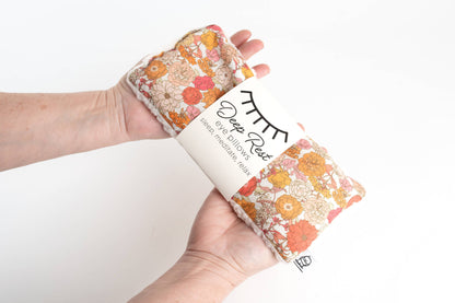 Hand holding Liberty Weighted Eye Pillow in floral design, perfect for tension relief, anxiety reduction, and restful sleep routines.