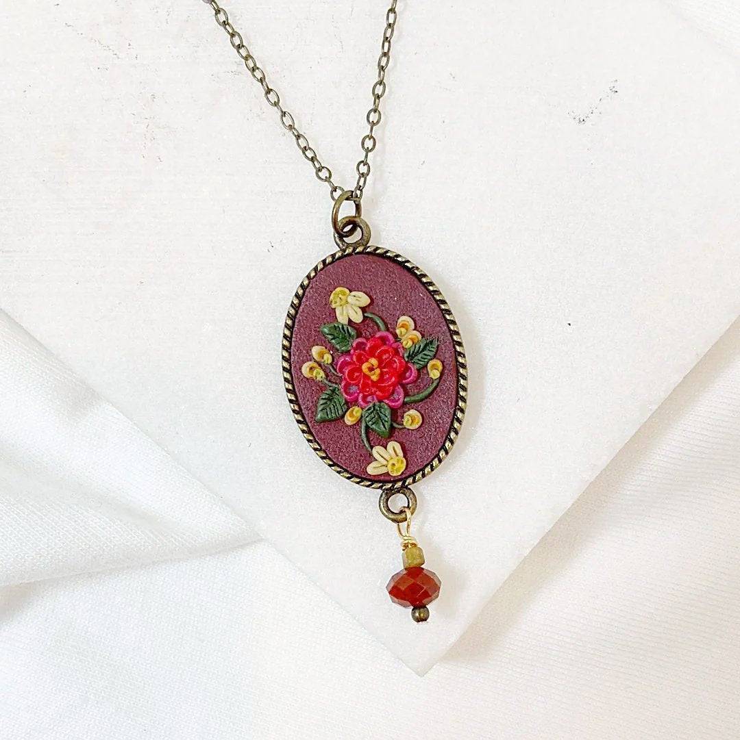 Uni-T Polymer Clay Floral Necklace with red and yellow hand-sculpted flowers on maroon pendant, finished with a red gemstone drop.