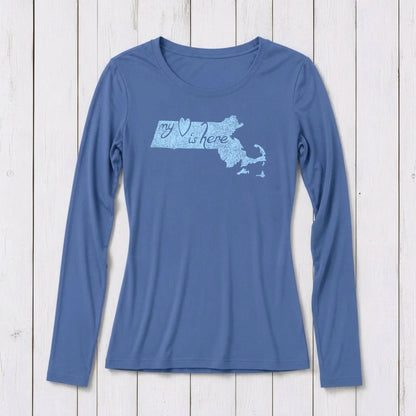 Blue long sleeve T-shirt with a graphic of Massachusetts map and the phrase 'my heart is here' in script, made of organic cotton and bamboo blend, on white wooden background