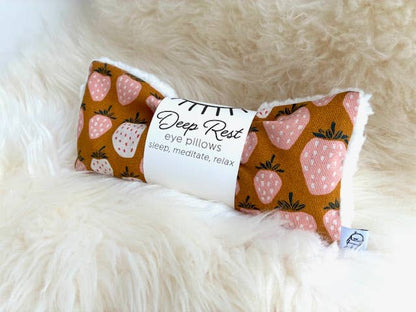 Strawberry-themed eye pillow on plush surface