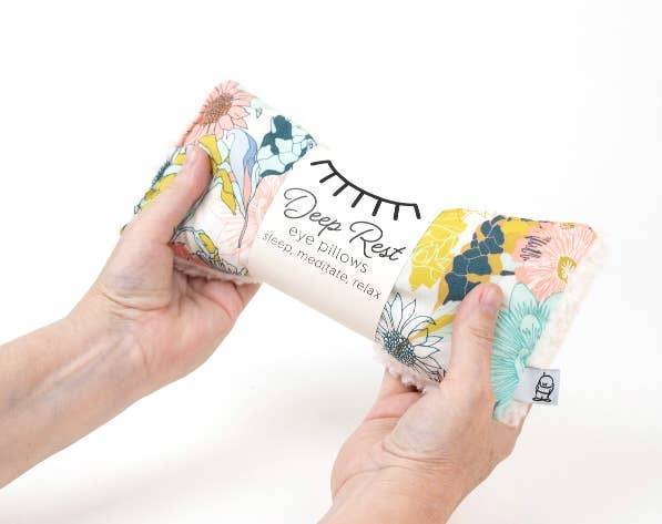 Hands holding Deep Rest Eye Pillow - Weighted for Relaxation in Meadow floral pattern, perfect for stress relief and meditation.