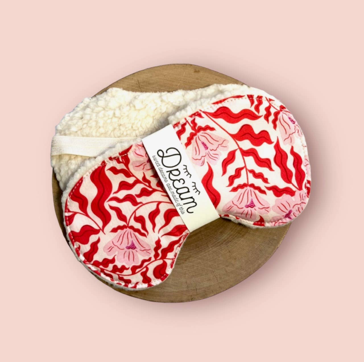 Red Vine Edition Sweet Dreams Sleep Mask with soft minky back and cotton front, styled on a round wooden board with pink background for product display.