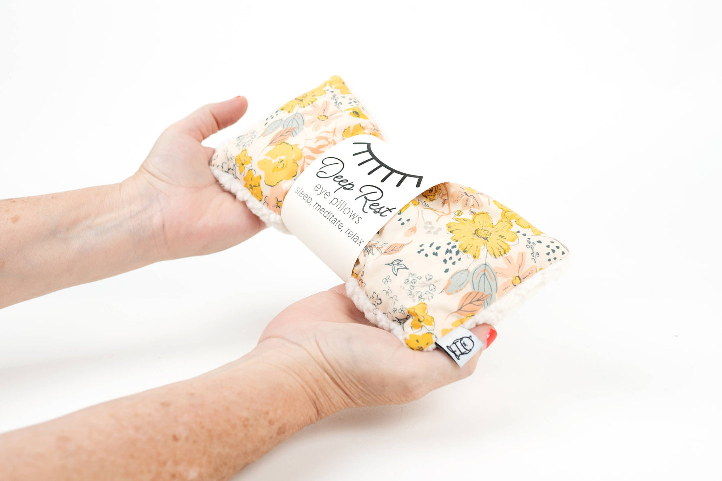 Hands holding Deep Rest Eye Pillow - Relaxation & Sleep Aid, showcasing its soft fabric and floral print for calming self-care use.