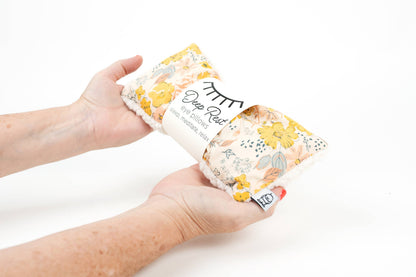 Hands holding Deep Rest Eye Pillow - Relaxation & Sleep Aid, showcasing its soft fabric and floral print for calming self-care use.