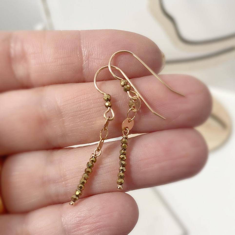 Hand holding Dainty Gemstone Earrings - Gemstone Silver Earrings with glittering hematite stones and gold hooks. Lightweight and perfect for daily wear.