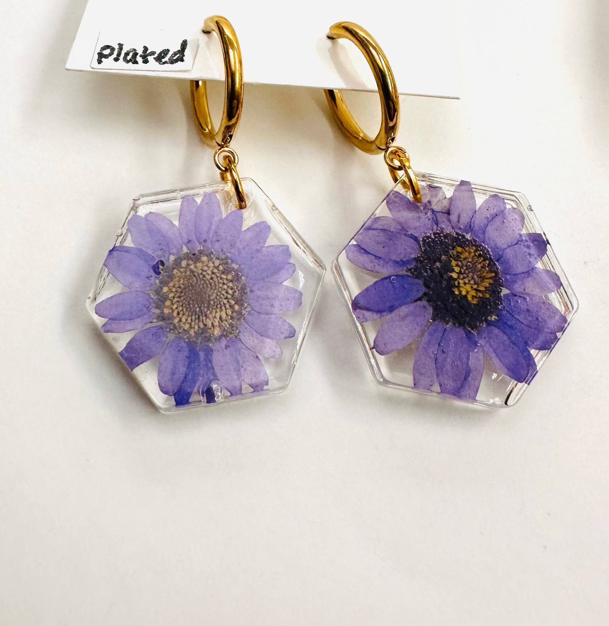Hexagon resin earrings with purple daisy flowers and gold hoops. Real flower earrings with a modern floral design.