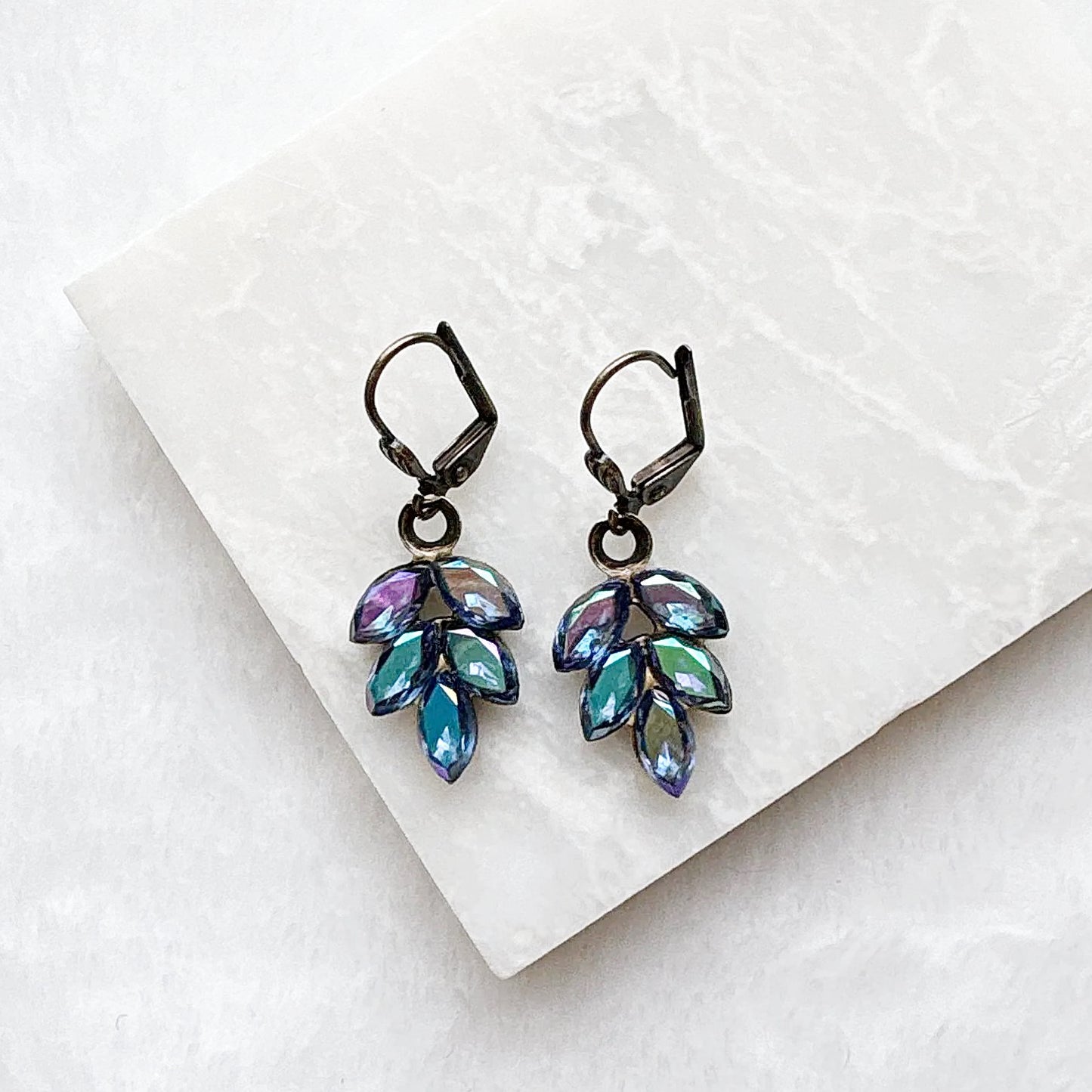 Close-up of vintage brass crystal dangle earrings with colorful iridescent beads
