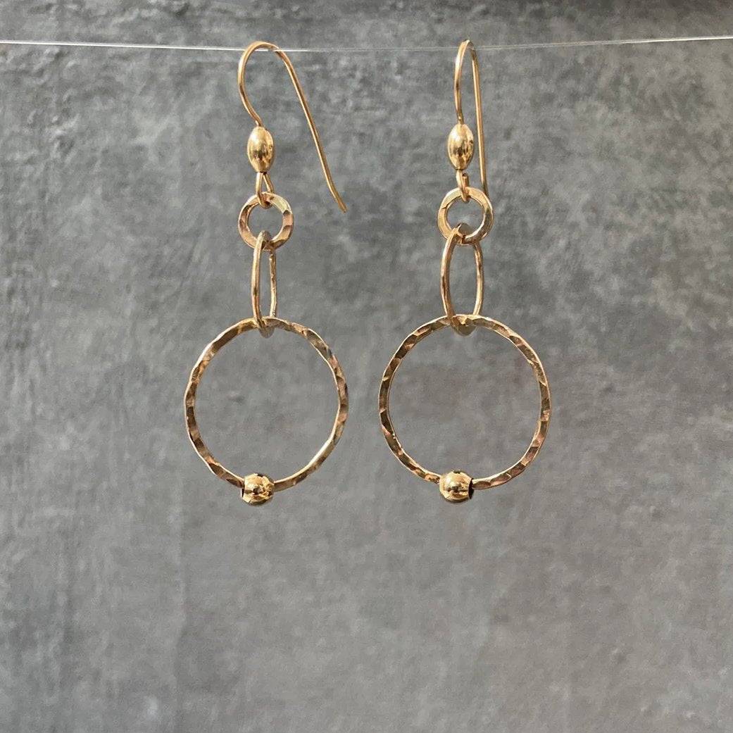 HoopLink Earrings in gold with hammered texture and soldered links, hanging against a gray background. Durable design for everyday wear.
