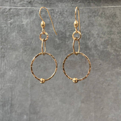 HoopLink Earrings in gold with hammered texture and soldered links, hanging against a gray background. Durable design for everyday wear.