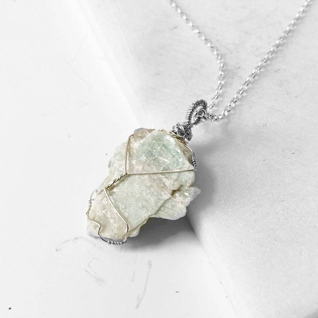 Close-up of handcrafted Amazonite pendant wrapped in silver wire, highlighting the raw gemstone's natural beauty and calming properties.