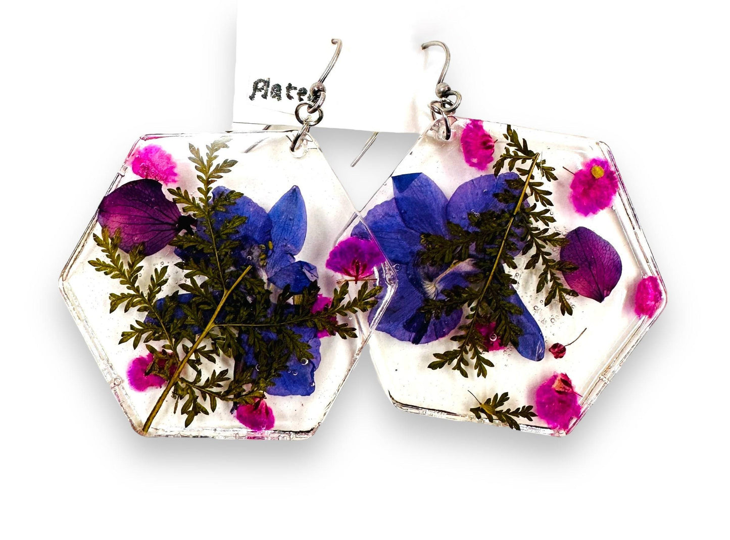 Hexagon resin earrings with purple and pink flowers and silver hooks. Nature-inspired pressed flower earrings with bold colors.