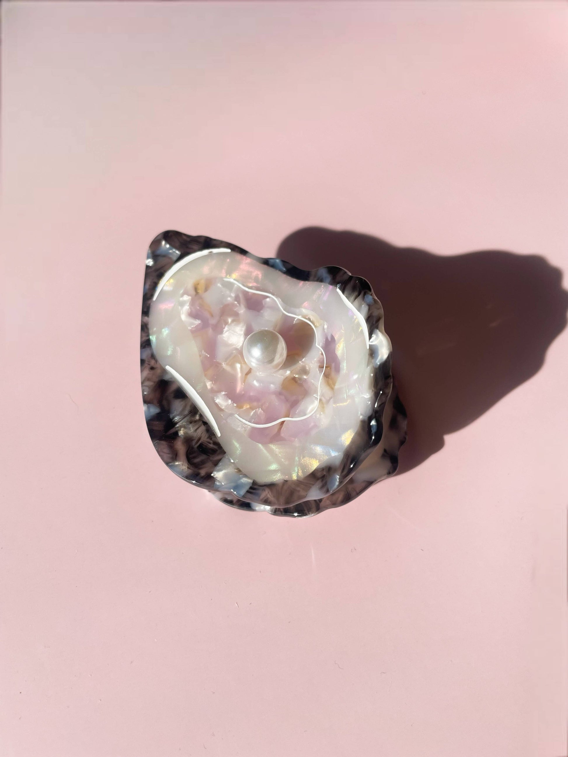 Line&Co Oyster Claw Clip with pearl detail on pink background, showcasing iridescent shell design. Elegant hair accessory for stylish looks.
