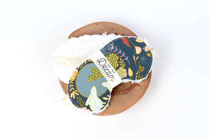 Nightfall Sleep Mask from Sweet Dreams with forest-themed cotton front and white minky back, displayed on a wooden tray.