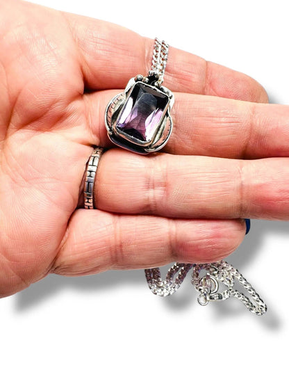 Close-up of Amethyst Grapes Wine Necklace held in hand, highlighting the rich purple gemstone and intricate silver grapevine detailing.