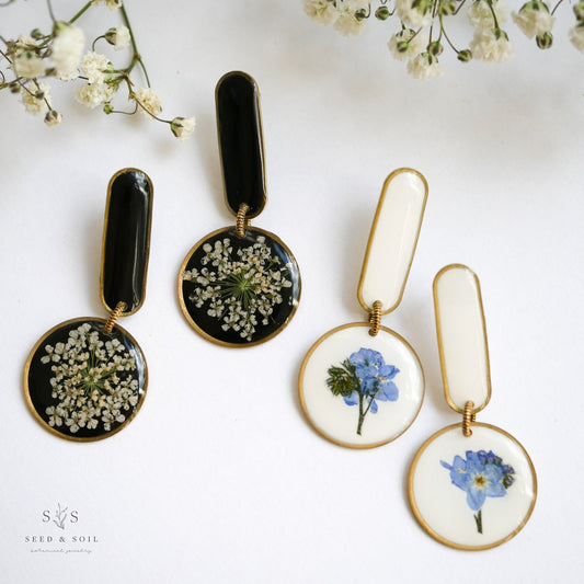Modern Artist Earrings with funky floral designs in black and white backgrounds, featuring real flowers and stainless steel posts.