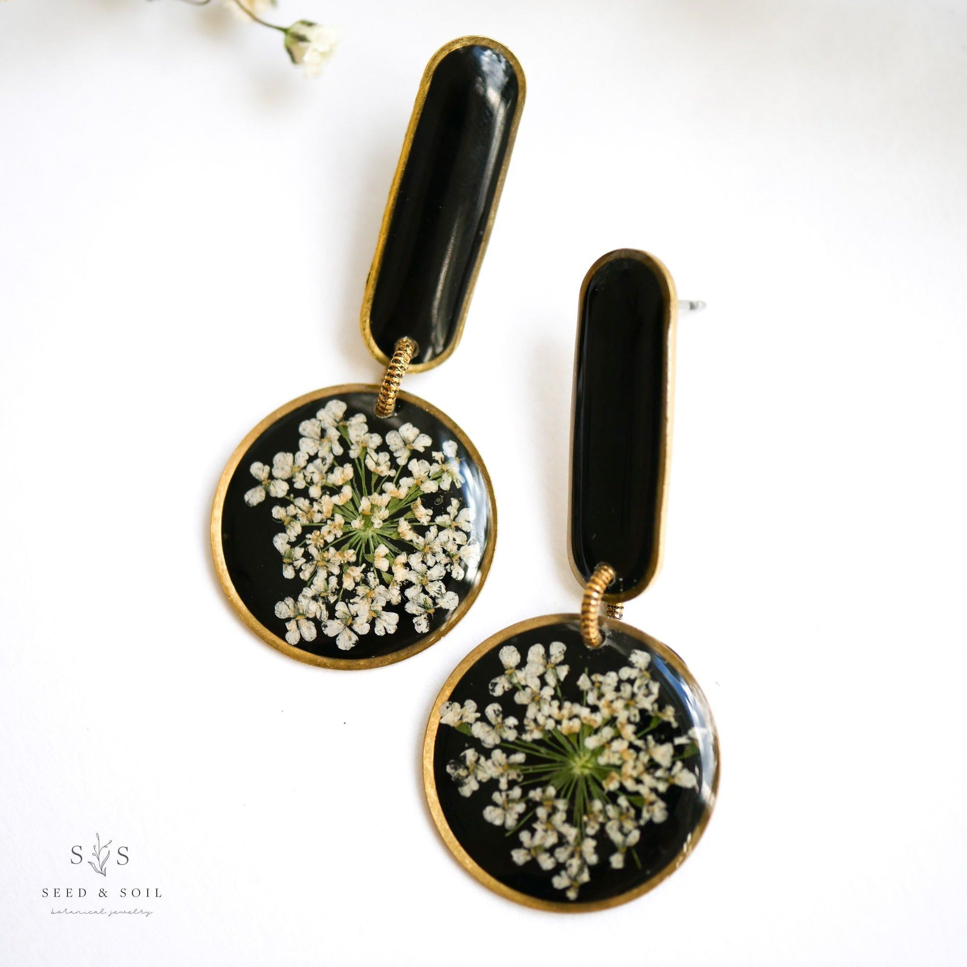 Black background Modern Artist Earrings with real white flowers and stainless steel posts, perfect for creative souls.