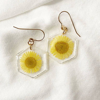 Hexagon resin earrings with yellow daisy flowers on white fabric. Real flower jewelry from the Pressed Flower Earrings collection.