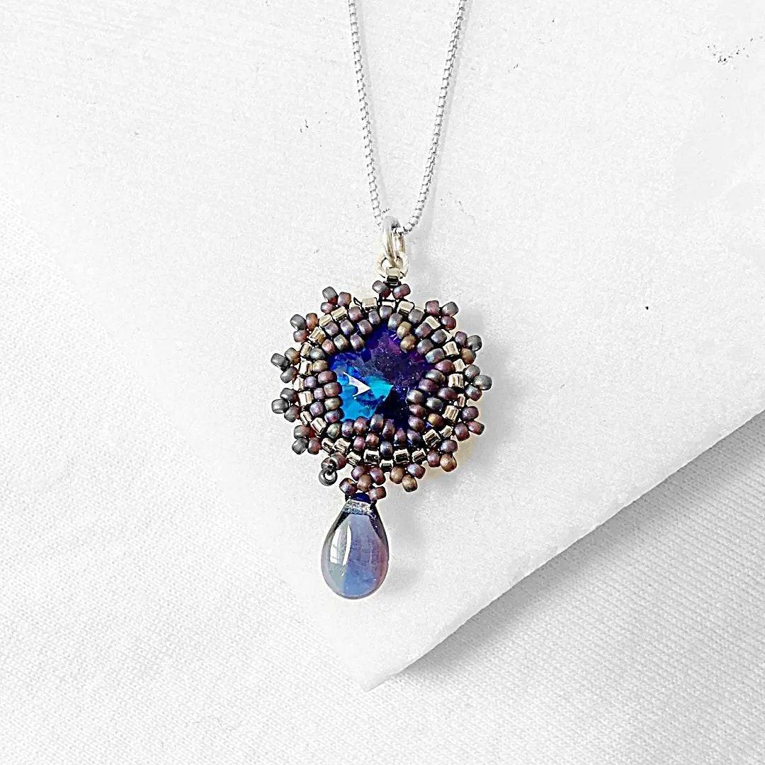 Close-up of beaded crystal necklace pendant with intricate detailing and a teardrop charm, showcasing fine craftsmanship.