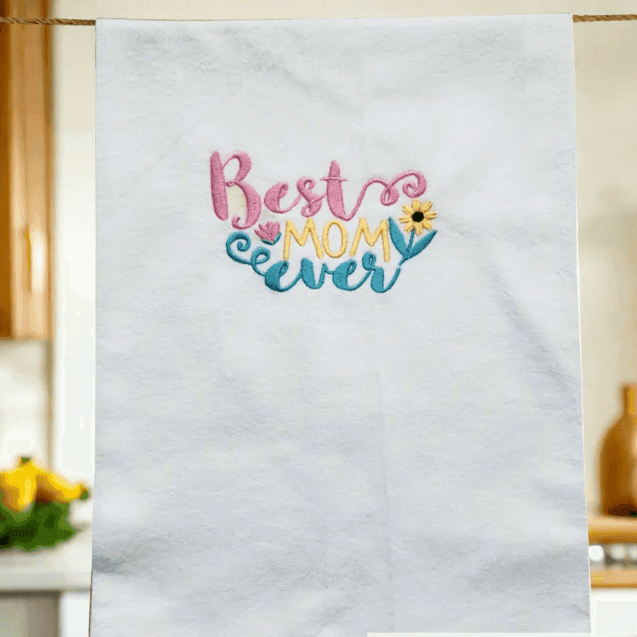 Best Mom Ever Towel - Embroidered Gift | Flour Sack 27"x27" hanging in a cozy kitchen, showcasing colorful embroidery for Mother's Day or birthdays.